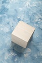 Bright wood cube on white and blue painting surface. Wooden cube and a piece of fine art studio shot. Royalty Free Stock Photo