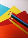 Bright wood pencil crayons on different colors of construction paper on a white background