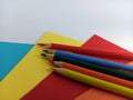 Bright wood pencil crayons on different colors of construction paper on a white background