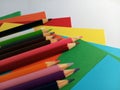 Bright wood pencil crayons on different colors of construction paper on a white background