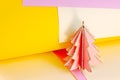 Bright wooden pink Christmas tree on colorful magenta and yellow paper swirls abstract background with copy space. Simple New Year