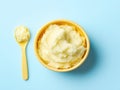Bright yellow baby bowl with creamy mashed potatoes on soft blue background Royalty Free Stock Photo
