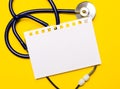 On a bright yellow background, a blue stethoscope and a sheet of paper with a place to insert text. Medical concept