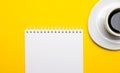 On a bright yellow background, a white cup with coffee and a blank white notebook with a place to insert text or illustrations. Royalty Free Stock Photo