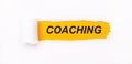 On a bright yellow background, white paper with a torn stripe and the inscription COACHING Royalty Free Stock Photo