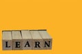 Bright yellow background with wooden alphabet blocks spelling out the word 'learn' Royalty Free Stock Photo