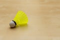 Bright yellow badminton birdie or shuttlecock on soft brown background with copy space