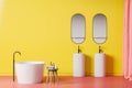 Bright yellow bathroom interior, tub and sinks