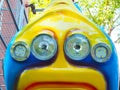 Bright yellow-blue attraction with round headlights in amusement park. Closeup photo