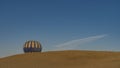 A bright yellow-blue balloon rises above a sand dune. Royalty Free Stock Photo