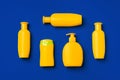 Bright yellow bottles of sunscreen product on dark blue paper background Royalty Free Stock Photo