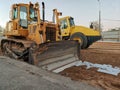 a bright yellow bulldozer shovels sand on the road