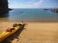 A bright yellow canoe sitting empty on a golden sand beach in a cove on the Able Tasman National Park
