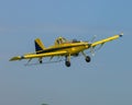 Bright yellow crop duster airplane soaring across a pristine blue sky