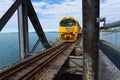 Bright yellow diesel train entering truss bridge