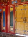 Bright yellow doors against a colourful red, blue and green wall with golden details Royalty Free Stock Photo