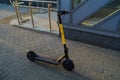 A bright yellow electric scooter stands in the city center for people to ride. rent transport for movement. charged from the mains