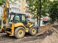 Bright, yellow excavator digs a hole in the sand. construction machinery. reliable road and pit construction vehicle drives