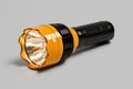 Bright yellow flashlight with a black handle on a gray background Royalty Free Stock Photo