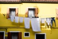 Bright yellow house with shutters and washing hanging out on the island of Burano, Venice. Royalty Free Stock Photo