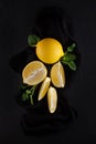 Bright yellow lemons, slices, rustic food photography on dark slate plate kitchen table