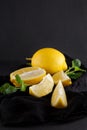 Bright yellow lemons, slices, rustic food photography on dark slate plate kitchen table
