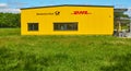 Bright yellow location building of a German logistics company behind a green field, post office, parcel distributor Royalty Free Stock Photo