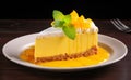 A bright yellow mango cheesecake with a smooth topping, fresh mango pieces, and a mint leaf on a white plate over dark wooden