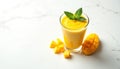 Bright yellow mango smoothie in glass with mint leaf. Fresh mango fruit cubes and half mango placed on white marble surface. Royalty Free Stock Photo