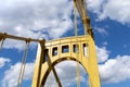 Bright yellow metal bridge structure against a blue sky with clouds, bright sunny day Royalty Free Stock Photo