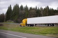 Bright yellow modern semi truck trailer on fencet exit to highway road Royalty Free Stock Photo