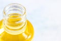 Bright yellow oil in plastic trasparent bottle on light background close up with copy space.