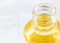 Bright yellow oil in plastic trasparent bottle on light background close up with copy space.