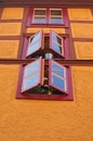 Bright yellow orange wall of rustic old house with three windows and fresh flowers. Loket, Czech Republic Royalty Free Stock Photo