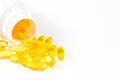 Bright yellow oval pills with fish oil omega-3 vitamin in the medical bottle on white background with copy space. Royalty Free Stock Photo