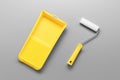 Bright Yellow painting tray cuvette and paint roller on grey background