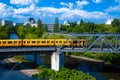 A bright yellow passenger train rides across a bridge over a river Royalty Free Stock Photo