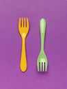 Bright yellow plastic spoon and fork on a blue background. Flat lay.Yellow and green plastic forks on a purple background. Minimal Royalty Free Stock Photo