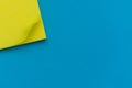 Bright yellow posted note on bright blue flat lay background for education or business organization and reminder concepts Royalty Free Stock Photo