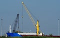 Bright yellow quay crane at work in a harbour dock: Near there is a black crane. Royalty Free Stock Photo