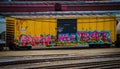 Bright yellow railroad car tagged with graffiti