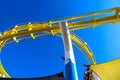 A bright yellow rollercoaster track with a gorgeous blue sky at Santa Monica Pier in Santa Monica