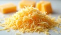 Bright yellow shredded cheese forms a mound on a clean white surface. Three blocks of solid cheese sit out of focus in background Royalty Free Stock Photo