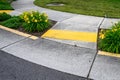 Bright yellow sidewalk guides on a corner crossing, with yellow daylilies planted on either side of the entrance Royalty Free Stock Photo