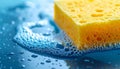 Bright Yellow Sponge Surrounded by Soap Suds on a Smooth Blue Surface Studio Shot Royalty Free Stock Photo