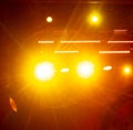 Bright yellow spotlights at a concert at night.