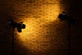 Bright yellow spotlights near brick wall in dark room, space for text Royalty Free Stock Photo