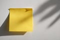 Bright yellow sticky note on white wall creating clean and simple workspace atmosphere Royalty Free Stock Photo
