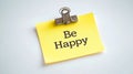A bright yellow sticky note with be happy message on a clean white background for motivation Royalty Free Stock Photo