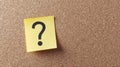 Question Mark on Yellow Sticky Note Attached to Tan Cork Board Surface Royalty Free Stock Photo
